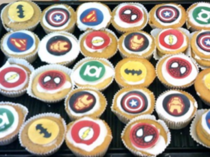 a tray of cupcakes decorated with famous figures and logos from comic books and graphic novels